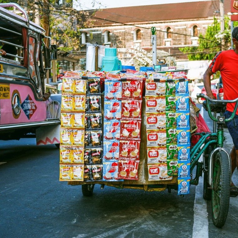 Isang vendor na may bisikletang puno ng mga sachet sa kalye